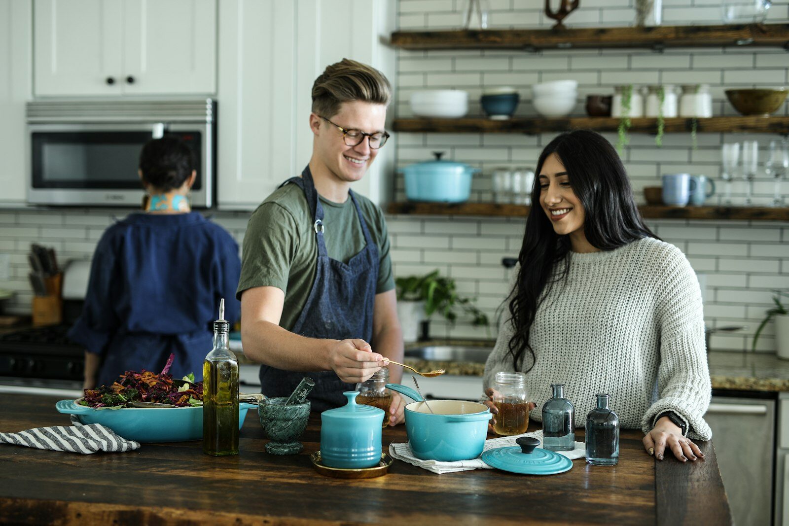 Smiling couple cooking a meal together in a bright lived-in home kitchen